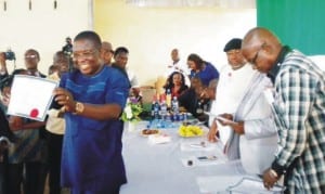 Mr Peter Madubueze, the House of Representatives-elect for Anambra East and West Federal Constituency displays his Certificate of Return after receiving it from Inec official in Awka last Friday.